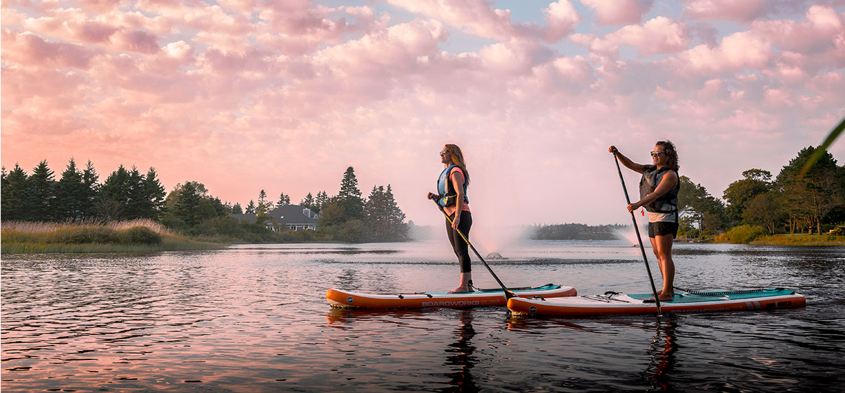 Two women paddle boarding in Nova Scotia Deux femmes font du paddle board en Nouvelle-Écosse